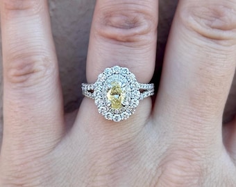 May include: A diamond ring featuring a central oval-cut yellow diamond, surrounded by a double halo of smaller white diamonds. The ring has a split shank band, also adorned with diamonds, creating a sparkling and elegant design.