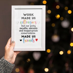 May include: White framed print with the text "WORK MADE US colleagues but our potty mouths, sarcasm and inappropriate conversations MADE US friends" with a black heart and a red heart on either side of the word "friends".