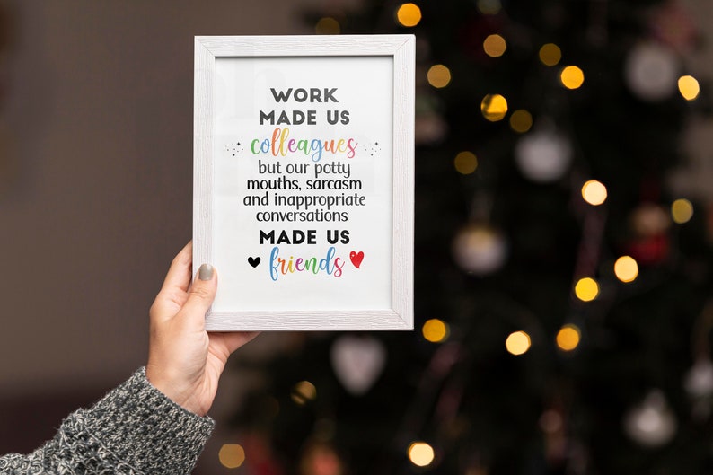 May include: White framed print with the text "WORK MADE US colleagues but our potty mouths, sarcasm and inappropriate conversations MADE US friends" with a black heart and a red heart on either side of the word "friends".