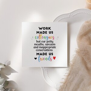 May include: A white card with the text "WORK MADE US colleagues but our potty mouths, sarcasm and inappropriate conversations MADE US friends" in black text with a rainbow colored "colleagues" and red hearts around the word "friends".