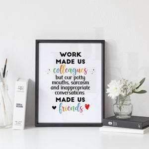 May include: A black framed print with a white background and the text "WORK MADE US colleagues but our potty mouths, sarcasm and inappropriate conversations MADE US friends" in black with rainbow colored letters. There are two red hearts at the bottom of the text.