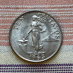 May include: Silver Philippine coin with a woman holding a hammer and an anvil. The coin reads "TEN CENTAVOS" and "1963".