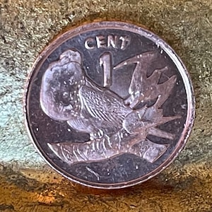 May include: A copper-colored coin with the number "1" and the word "CENT" printed on it. The coin features a bird with its wings spread out.