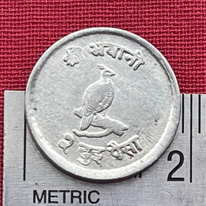 Può includere: Una moneta indiana d'argento con un uccello su un ramo. La moneta ha il testo "श्री अवधानी" scritto in hindi.