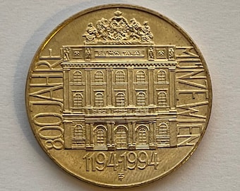Könnte beinhalten: Goldfarbene Münze mit einem Gebäude und dem Text "800 JAHRE MUNCHEN 1194-1994".