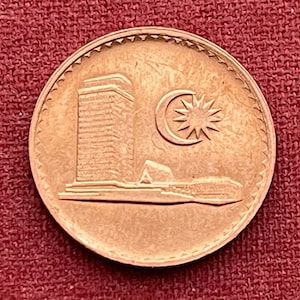 May include: A copper-coloured coin featuring a building and the Malaysian flag. The building is a modern skyscraper with a crescent moon and star above it.
