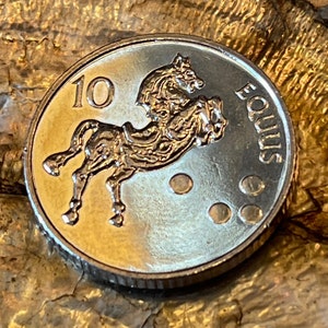 May include: A silver coin with a horse design and the text "10 EQUUS" on it.