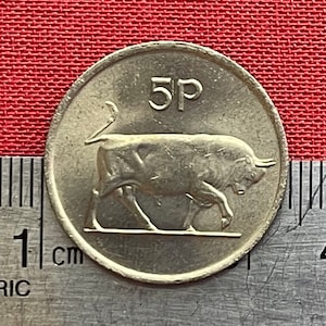 May include: A silver 5 pence coin from the United Kingdom featuring a bull with the inscription "5p" on the obverse.