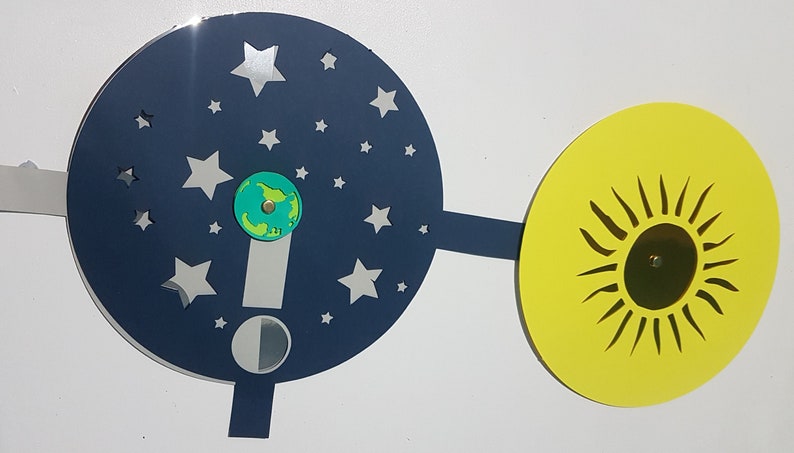 May include: A blue and silver cardboard disc with stars and a half moon, connected to a yellow disc with a black sun. The blue disc has a small green globe in the center.