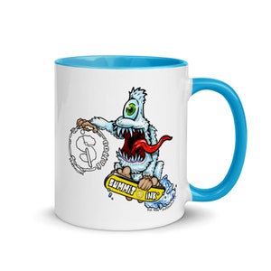 Pode incluir: Caneca de cerâmica branca com borda e alça azuis. A caneca apresenta uma ilustração de desenho animado de um monstro de um olho andando de skate com as palavras "Summit Ink" nela.