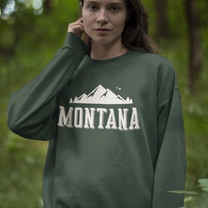 May include: A dark green sweatshirt with a white mountain graphic and the word "MONTANA" printed on the front.