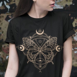 May include: Black t-shirt with a gold geometric design featuring a butterfly and crescent moons.