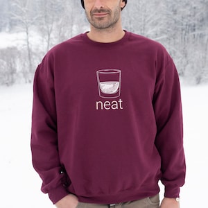 Pode incluir: Uma camisa de moletom vinho com um gr&aacute;fico branco de um copo de licor e a palavra "neat" impressa na frente.