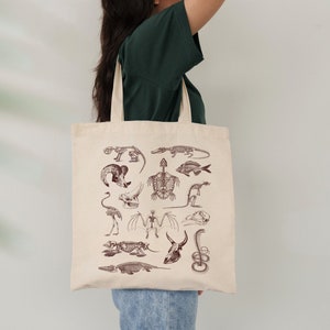 Peut inclure: Un sac fourre-tout beige avec un motif de squelettes d'animaux vari&eacute;s en brun. Les squelettes comprennent une tortue, un poisson, un oiseau, et plus encore.