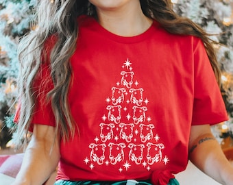 May include: Red t-shirt with a white Christmas tree design made up of dog silhouettes. The tree has a star on top and is surrounded by white stars.