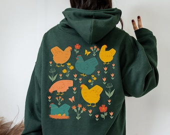 Puede incluir: Una sudadera con capucha verde oscuro con un estampado gráfico colorido de pollos y flores en la espalda.