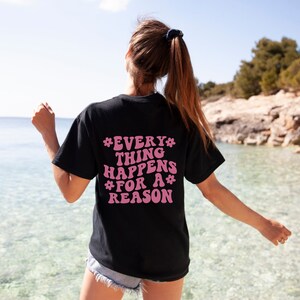 May include: A black t-shirt with a pink graphic that says "*EVERY* THING HAPPENS *FOR A* REASON"