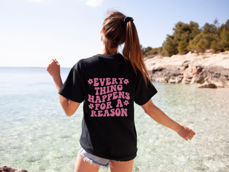 May include: A black t-shirt with a pink graphic that says "*EVERY* THING HAPPENS *FOR A* REASON"