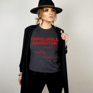 Puede incluir: Una camiseta gris oscuro con el texto "UNRELIABLE NARRATOR don't trust anything this person says" en rojo.