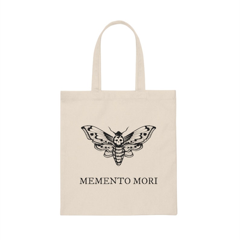 May include: A beige tote bag with a black and white moth design and the text "MEMENTO MORI" printed on the front.