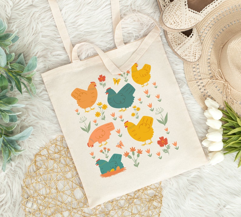 May include: A beige tote bag with a colorful design of chickens and flowers. The chickens are orange, yellow, and teal. The flowers are red, pink, and yellow.