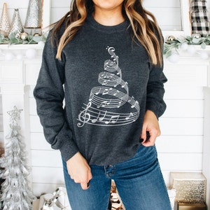 May include: A dark gray sweatshirt with a silver design of a Christmas tree made of musical notes.