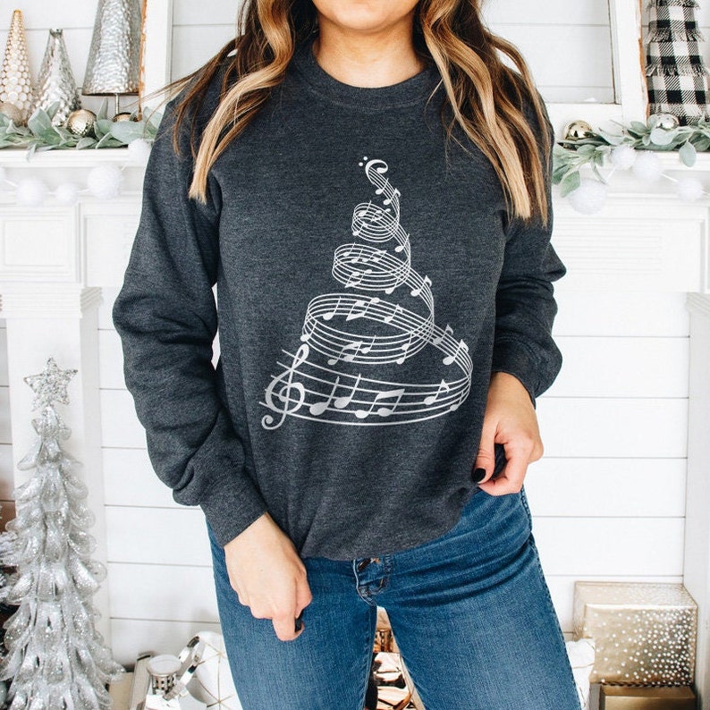 May include: A dark gray sweatshirt with a silver design of a Christmas tree made of musical notes.