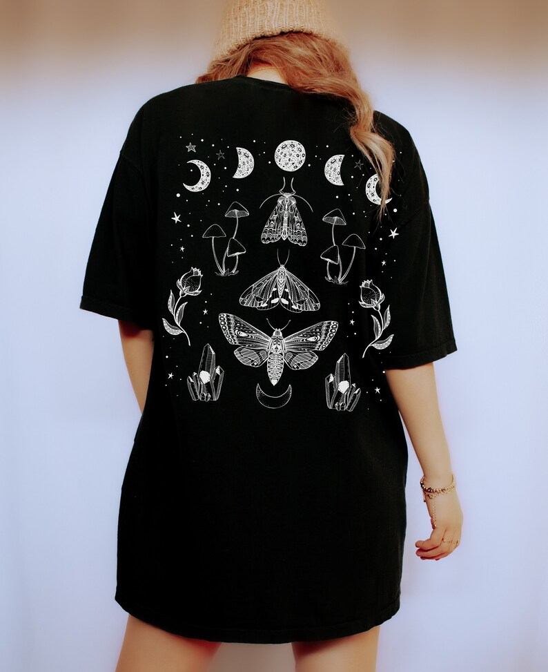 Op de afbeelding: Zwart oversized T-shirt met een witte grafische print van motten, paddenstoelen, kristallen en halve manen.