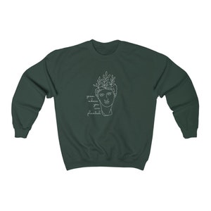 May include: A dark green sweatshirt with a white outline of a person's head with leaves on top. The text "grow where you are planted" is written below the image.