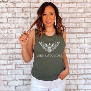 May include: A green sleeveless tank top with a white moth graphic and the text "MEMENTO MORI".
