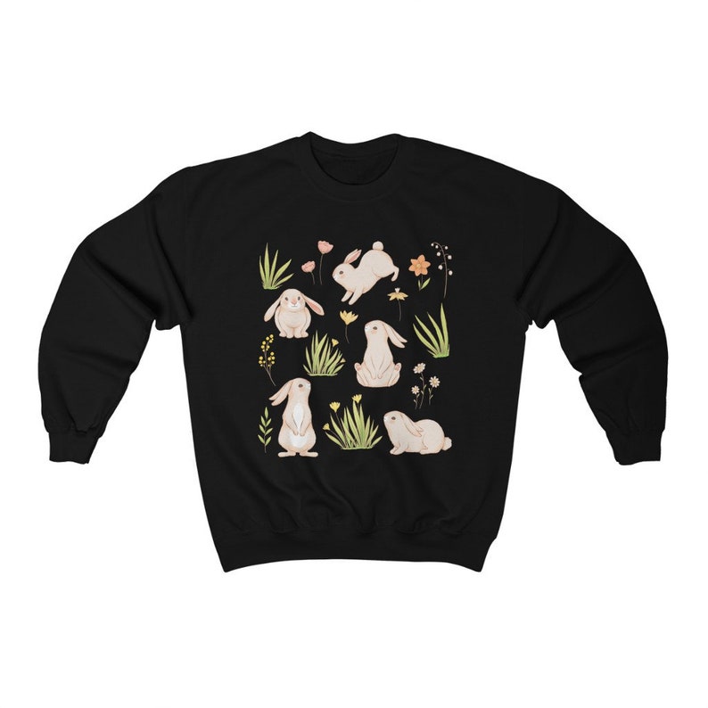 May include: Black sweatshirt with a white bunny rabbit and floral pattern. The bunnies are in different poses, including sitting, standing, and hopping. The flowers are in shades of pink, yellow, and orange.
