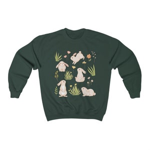 May include: A dark green sweatshirt with a white bunny rabbit pattern. The bunnies are surrounded by small flowers and green grass.