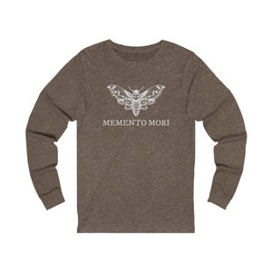 May include: A brown long-sleeved shirt with a white moth graphic and the text "MEMENTO MORI" printed on the front.