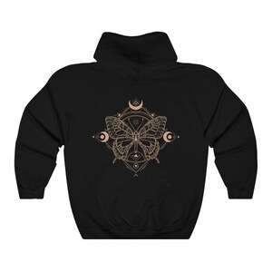 May include: Black hooded sweatshirt with a geometric design featuring a butterfly and crescent moons in a beige color.