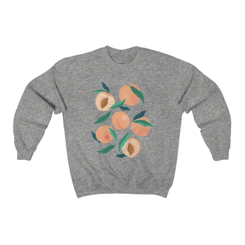 K&ouml;nnte beinhalten: Ein graues Sweatshirt mit einem Grafikdruck von Pfirsichen mit gr&uuml;nen Bl&auml;ttern. Die Pfirsiche sind hellorange.