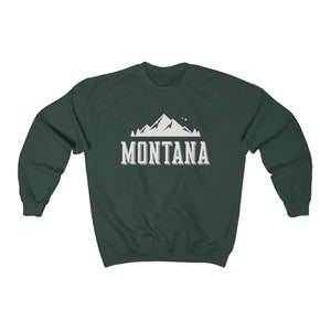 May include: A dark green sweatshirt with a white mountain graphic and the text "MONTANA" printed on the front.