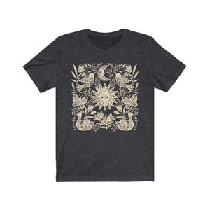 May include: A dark heather grey t-shirt with a cream-colored sun, moon, birds, butterflies, and floral design.
