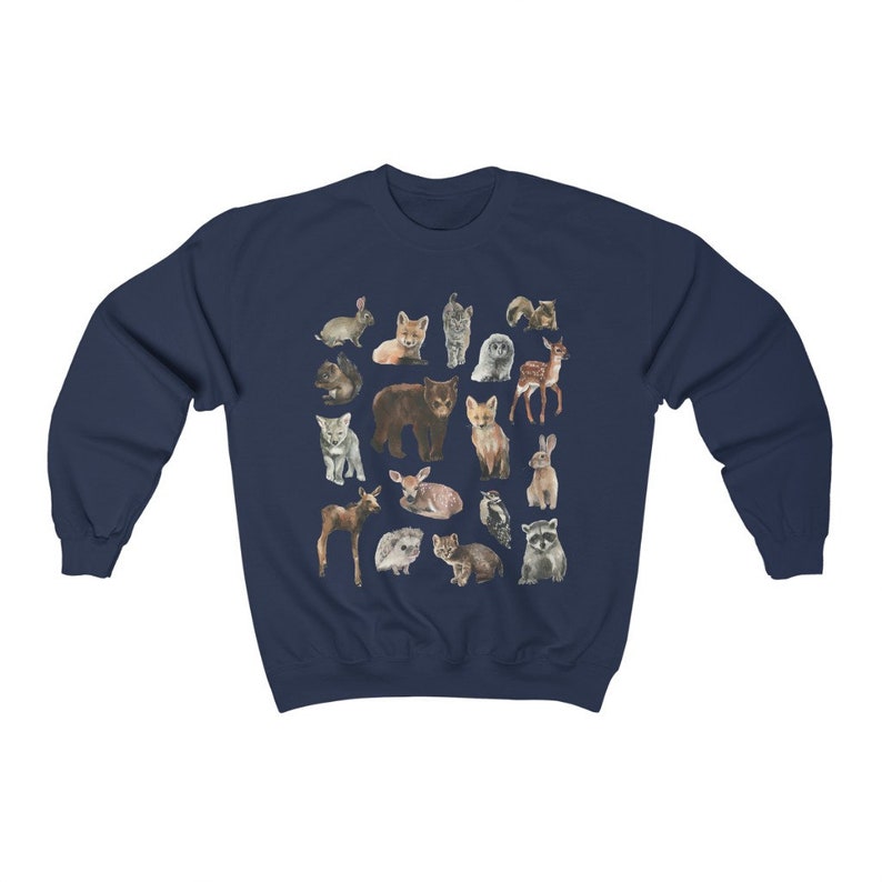 May include: A navy blue sweatshirt featuring a pattern of various woodland animals, including a bear, deer, fox, rabbit, raccoon, and owl. The animals are all depicted in a cartoon style and are arranged in a random pattern.