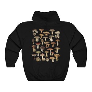 May include: Black hooded sweatshirt featuring a detailed illustration of various mushrooms in shades of brown, tan, red, and green. The design is centered on the back of the sweatshirt. The sweatshirt has a drawstring hood and a kangaroo pocket.