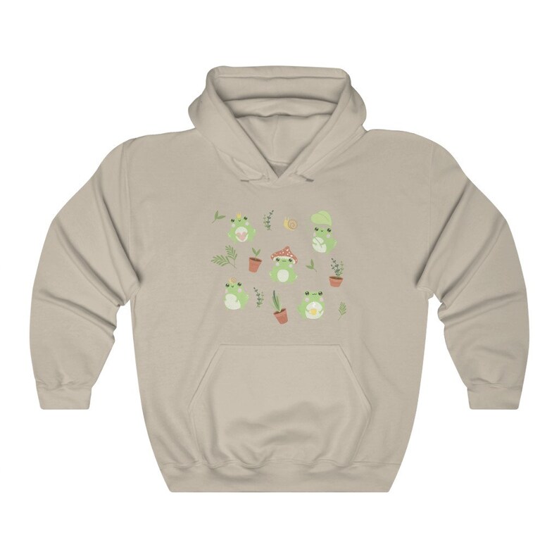 May include: A light beige hoodie with a pattern of green frogs, plants, and mushrooms. The frogs are wearing crowns, hats, and holding flowers.
