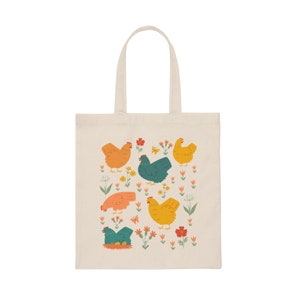May include: A white canvas tote bag with a colorful illustration of chickens and flowers. The chickens are yellow, orange, and blue, and the flowers are pink, red, and yellow.