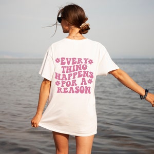 May include: White t-shirt with a pink graphic that says "*EVERY* THING HAPPENS *FOR A* REASON" on the back.
