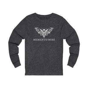 May include: A dark heather grey long-sleeved t-shirt with a white moth graphic and the text "MEMENTO MORI" printed on the front.