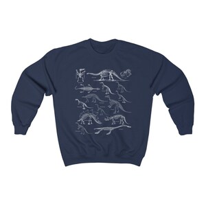 May include: Navy blue sweatshirt with a white print of dinosaur skeletons. The print features a variety of dinosaurs, including a Stegosaurus, Triceratops, and Brachiosaurus.