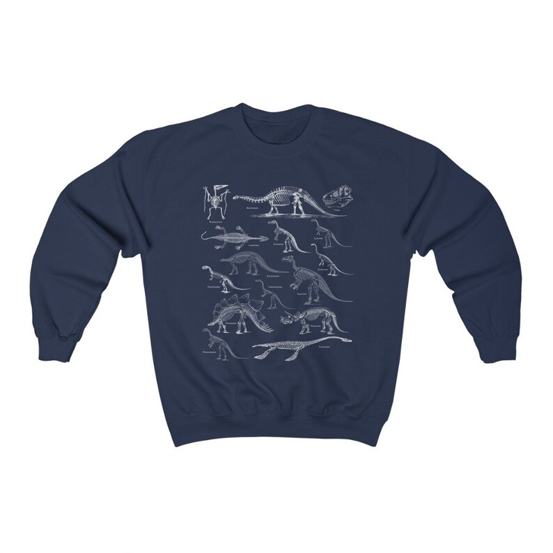 May include: Navy blue sweatshirt with a white print of dinosaur skeletons. The print features a variety of dinosaurs, including a Stegosaurus, Triceratops, and Brachiosaurus.