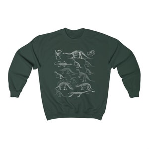 May include: A dark green sweatshirt with a white print of dinosaur skeletons. The print features a variety of dinosaurs, including a Stegosaurus, Triceratops, and Brachiosaurus.