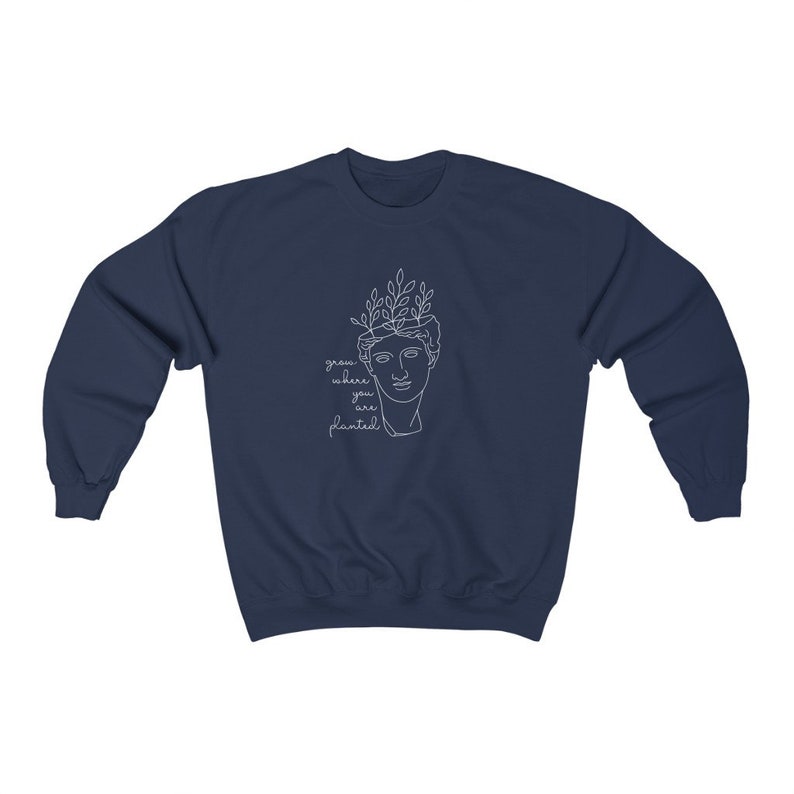 May include: Navy blue sweatshirt with a white outline of a bust with leaves growing from the top of the head. The text "grow where you are planted" is written below the bust.