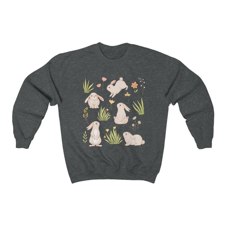 May include: A dark heather grey sweatshirt with a pattern of white bunnies and flowers. The bunnies are in various poses, including sitting, standing, and hopping. The flowers are in shades of pink, yellow, and orange.