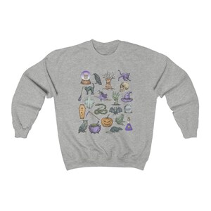 May include: A gray sweatshirt with a Halloween-themed design featuring a variety of spooky icons, including a ghost, a bat, a cauldron, a skull, a snake, a witch's hat, a raven, a pumpkin, a spider, a frog, a crystal ball, a coffin, a cat, a tree, a hand, a grave, and a potion bottle.
