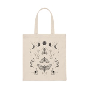 May include: A white canvas tote bag with a black and white design featuring moths, mushrooms, crystals, and moons.